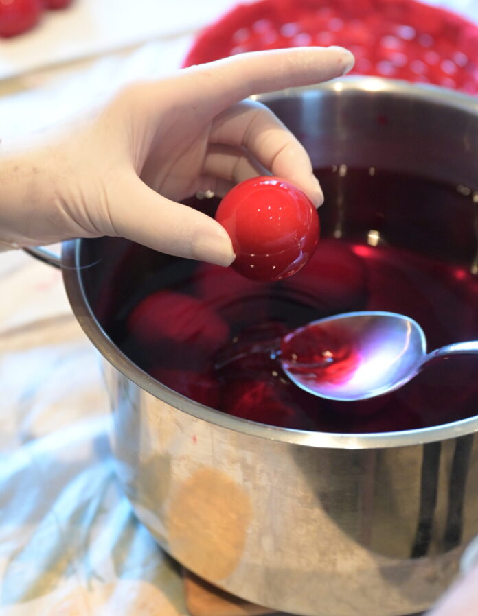 Βράζουμε τα αυγά και τα αφήνουμε να κρυώσουν καλά. Διαλύουμε τη βαφή σε ζεστό νερό με λίγο ξύδι, σύμφωνα με τις οδηγίες.Βάφουμε τα αυγά, τα τοποθετούμε σε χαρτί να στεγνώσουν και τα γυαλίζουμε με λάδι αν θέλουμε.